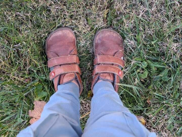 A top down view of a child's feet standing in grass wearing Lang.S kids barefoot boots with a wide toe box