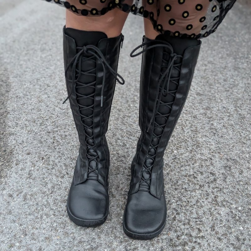 Front view of a pair of Shapen Abby tall lace up leather barefoot boots with a wide toe box and hidden eyelets.