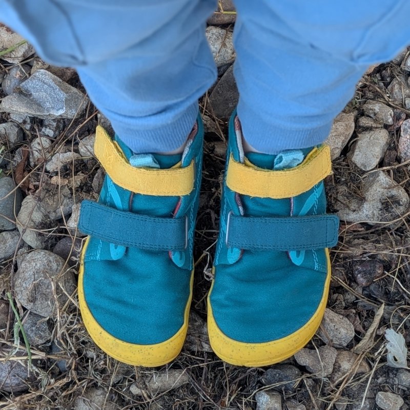 Wildling Shoes Filu in aquamarina close up on a young child's feet standing on rocky ground
