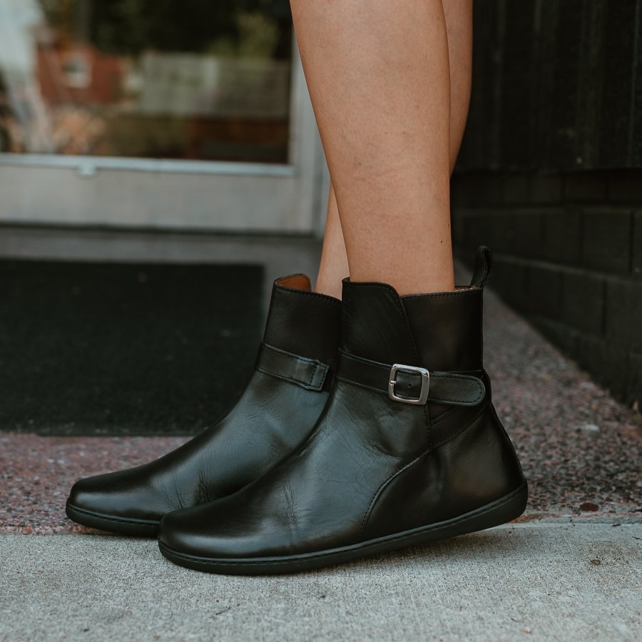 A clos eup of the side of a pair of Zaqq Riquet barefoot leather ankle boots with a buckle.