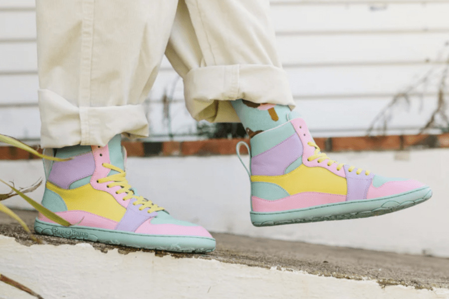 A person in pastel colorblock funky barefoot shoes from PaperKrane walking outside. The front foot is held up in a step and the zero drop outside is on display.