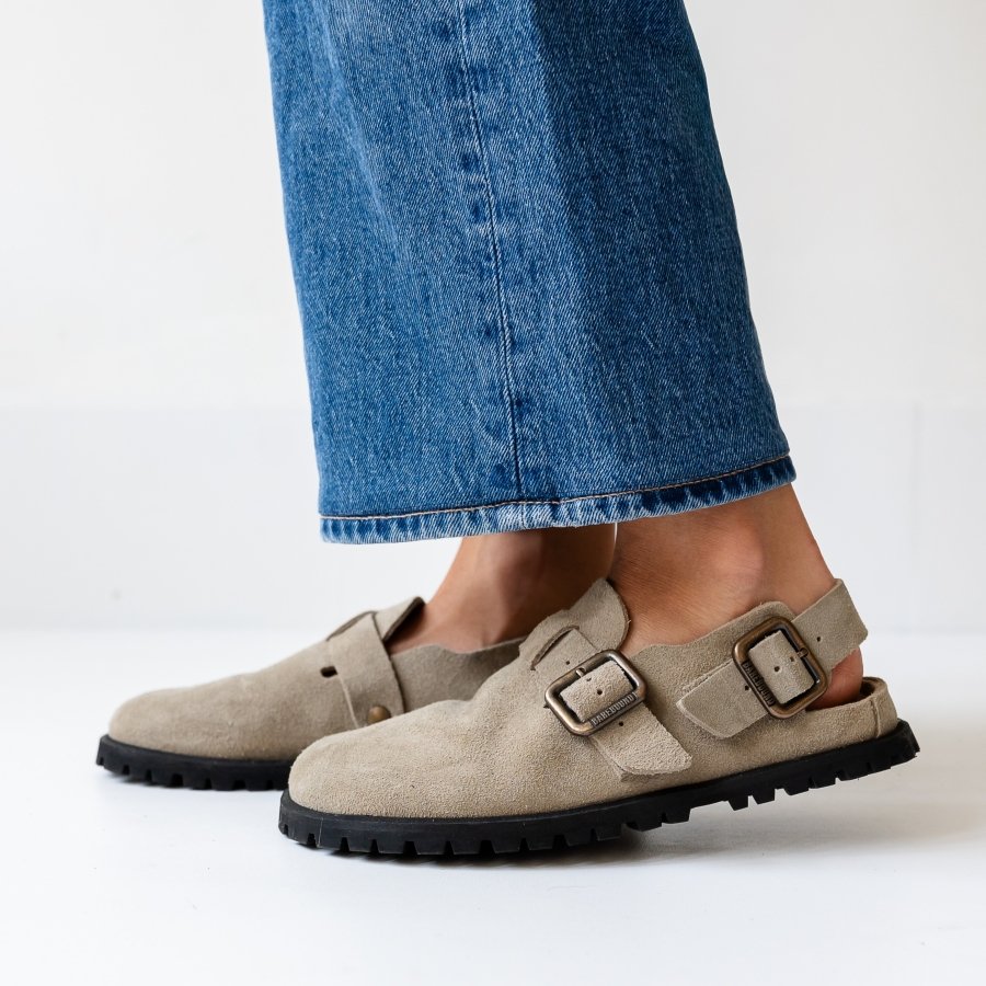 Close up side view of a person's feet in tan suede barefoot Ikaros Clogs from Barebound
