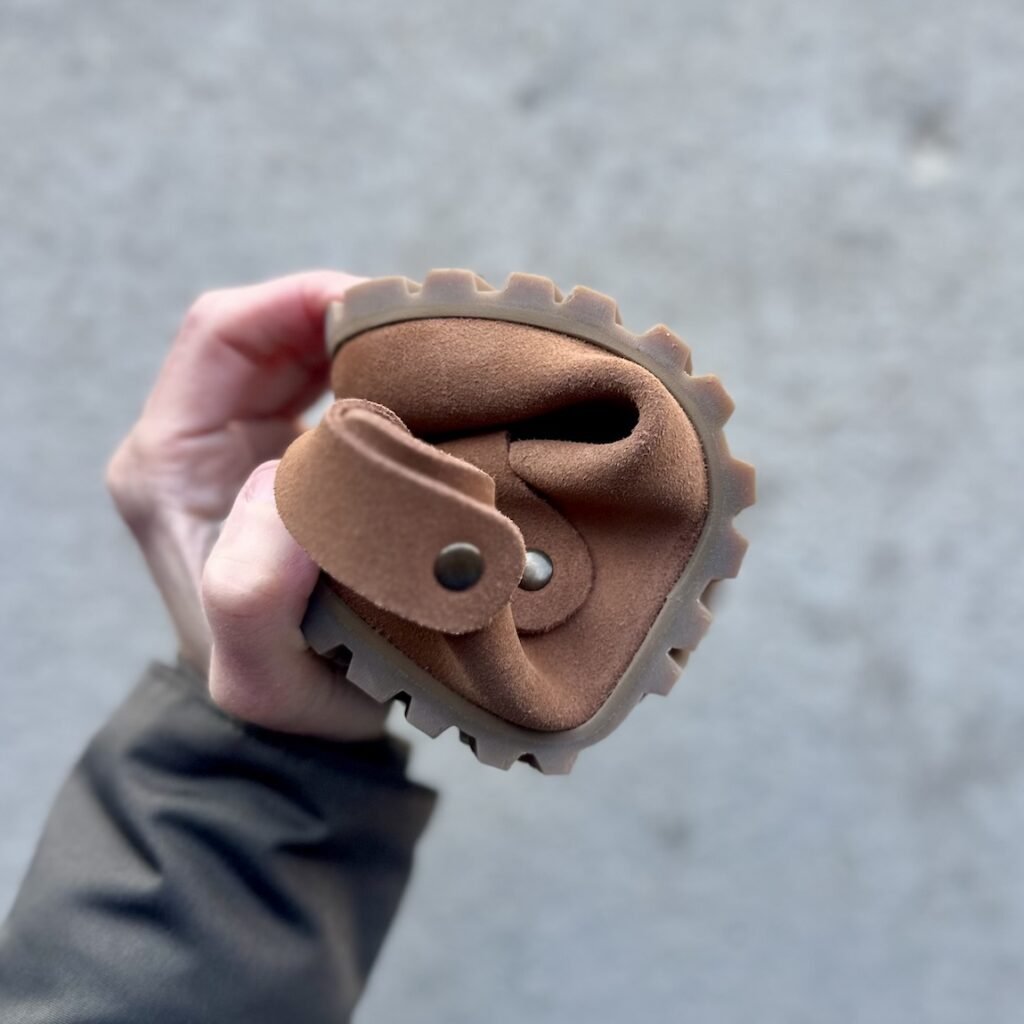 A close up of a hand rolling a Barebound Ikarus clog into a tight roll to show the flexibility.