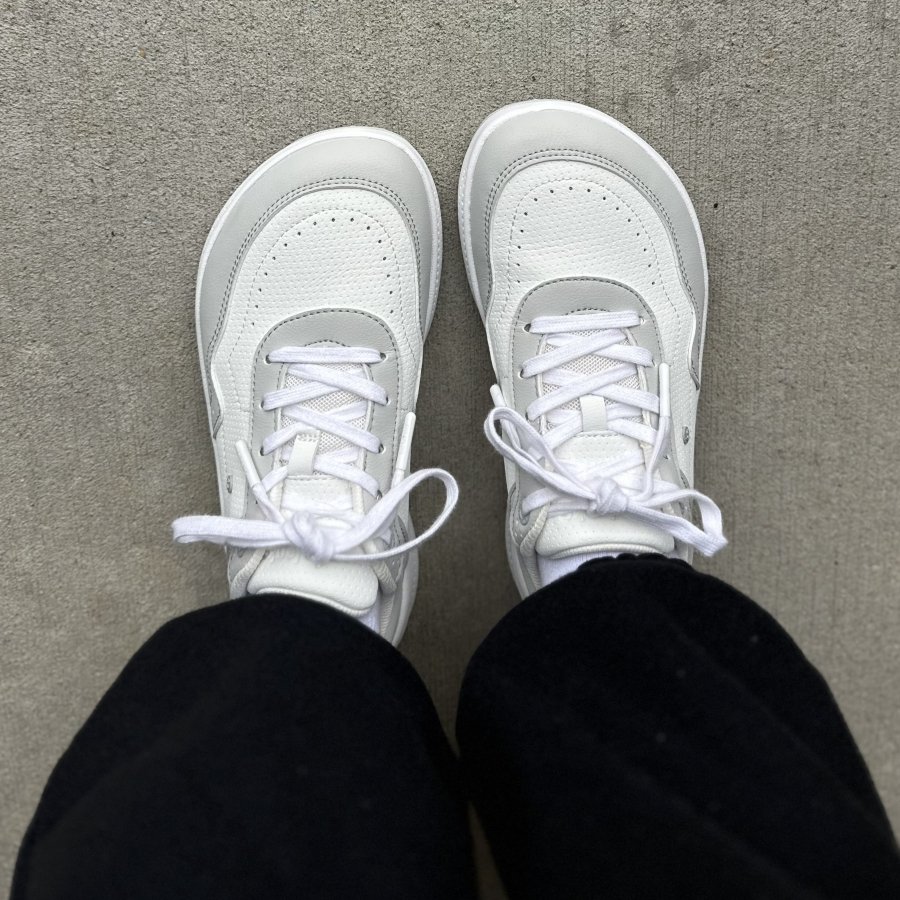 Top down view of a person's feet in a pair of white Be Lenka Recovery wide toe box but not barefoot sneakers.