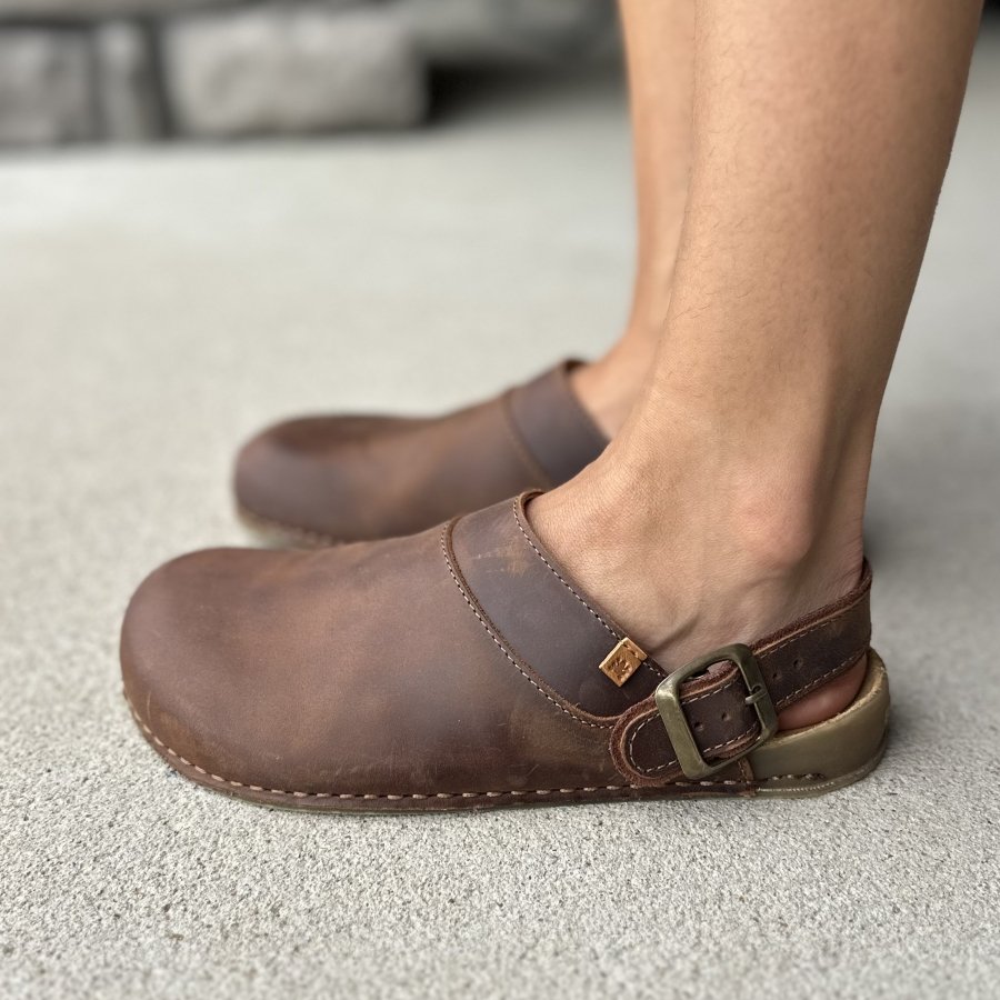 Side view of a pair of El Naturalista leather barefoot clogs with a super flexible flat outsole and a convertible heel strap.