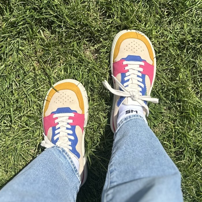 A top down view of a person in brightly colored Fleeters vegan barefoot sneakers with mustard, pink, and blue color blocking.