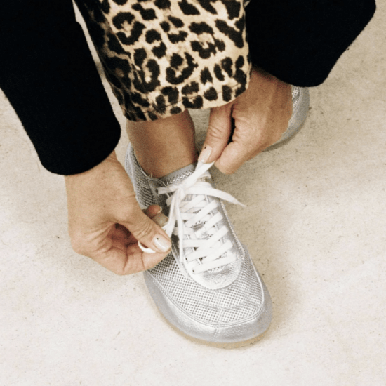 Close up of a person tying the laces on a pair of Ohne Project Kima ballerina sneakers in Silver
