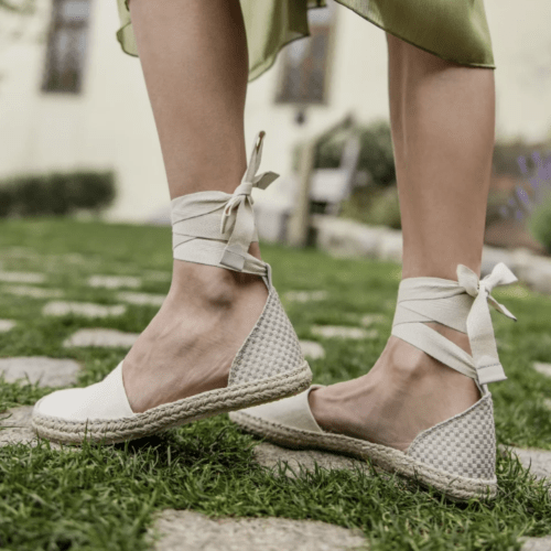 Side view of a person wearing Shapen Festa barefoot espadrille with ankle ties on grassy ground