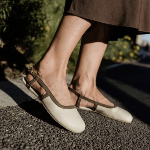 Close up side view of a person in Shapen Twiggy, an elegant wide toe sling back style in beige with brown edging.