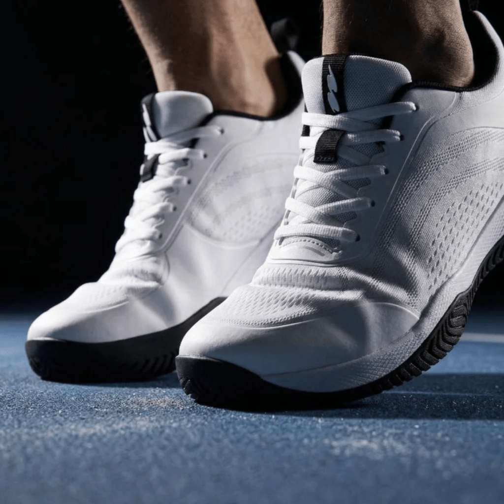 A person flexing onto their toes in Cuurt Wide toe box tennis sneakers in white.