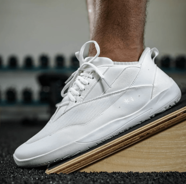 A side view of a person's feet on an inline block wearing Uncivilized Sneakers, a flat wide toe box option for the gym