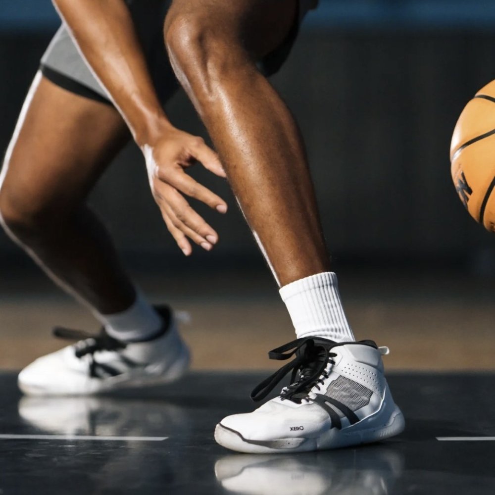 A waist down photo showing a person playing basketball in Xero X1 Barefoot Basketball Court Shoes. The person is doing a lateral stop with the zero drop stable court shoe with a wide toe box.