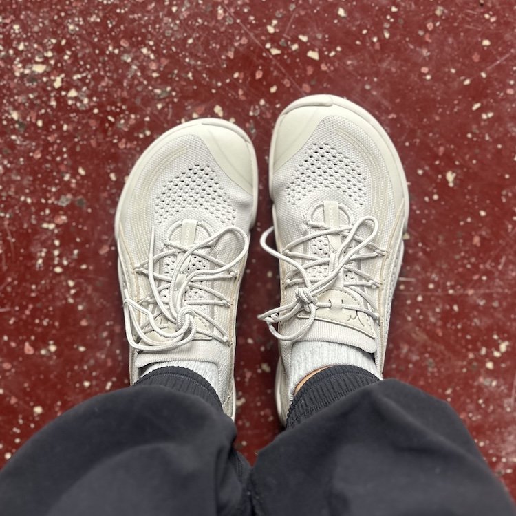 Top down close up picture of a person's feet in Lono Flow 2, a soft stretchy barefoot gym shoe with a wide toe box.