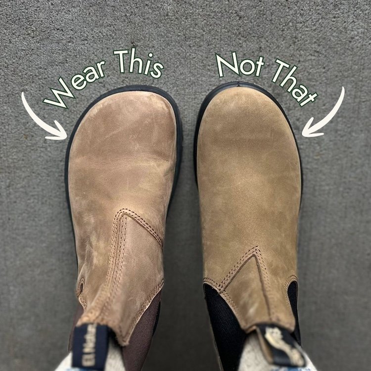 A top down view of a pair of feet wearing a different shoe on each foot. On the left is El Naturalista Nomada barefoot foot-shaped chelsea boot, on the right is a Blundstone Chelsea boot. You can see the toe box of the El Naturalista boot is foot shaped with a wide toe box and the Blundstone comes to a point and is narrower. The text "Wear This, Not That" is superimposed over the image.