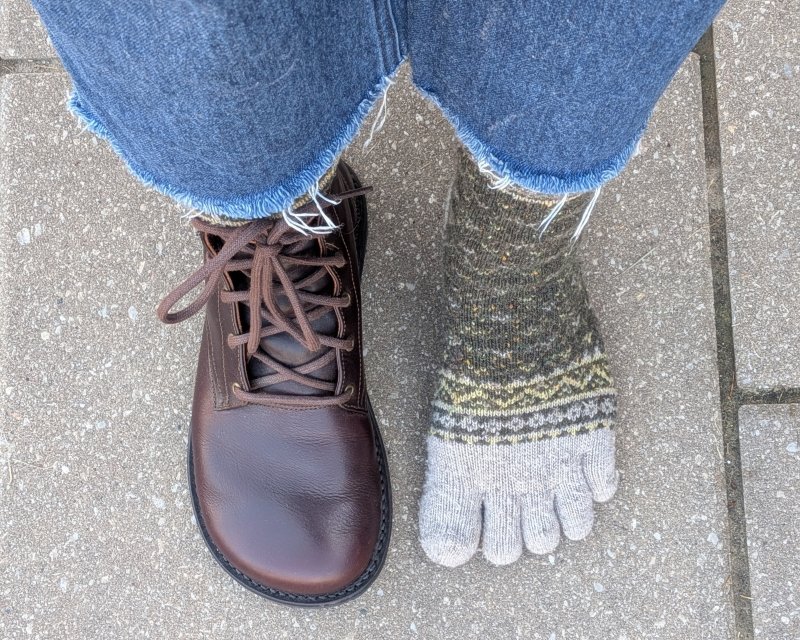 A top down view of a person's feet with one toe sock on and a Gaucho Ninja extra wide barefoot boot on the other foot
