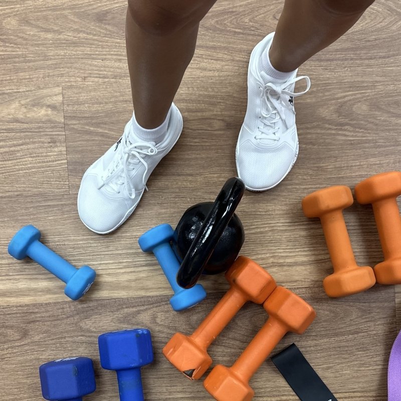 A top down look at a person's feet in Notorious Lift Radix Pro surrounded by several hand weights.