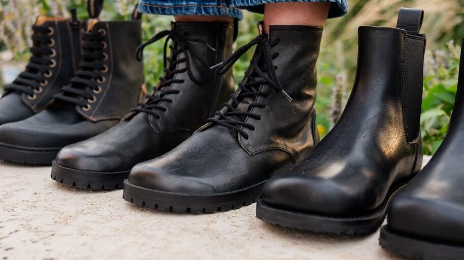 A trio of black barefoot boots with a person standing in the middle pair - Lang.S Kombat. Gaucho Ninja and El Naturalista brands are on the sides.