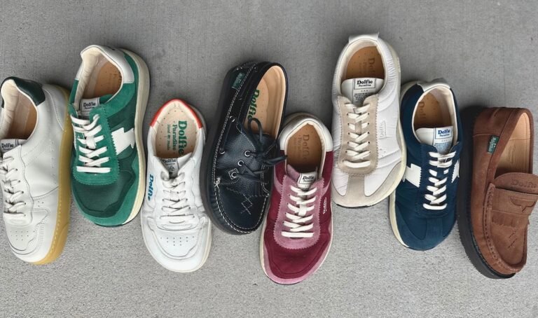 A row of different wide toe box Dolfie Paradise barefoot sneakers and shoes laid out on concrete in different colors and models.