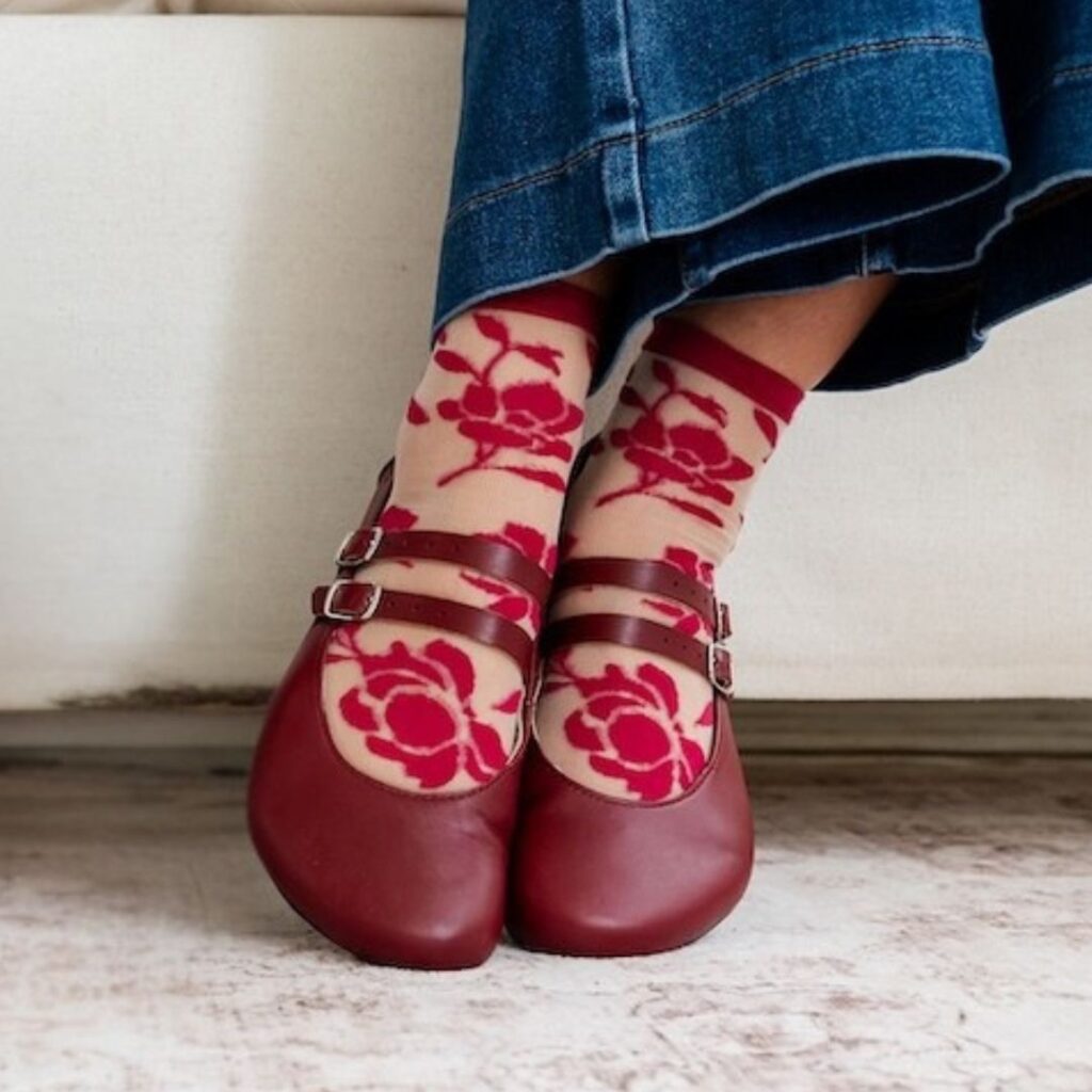 A person's feet in a pair of Crimson Jenon Villet double strap mary janes paired with sheer floral socks