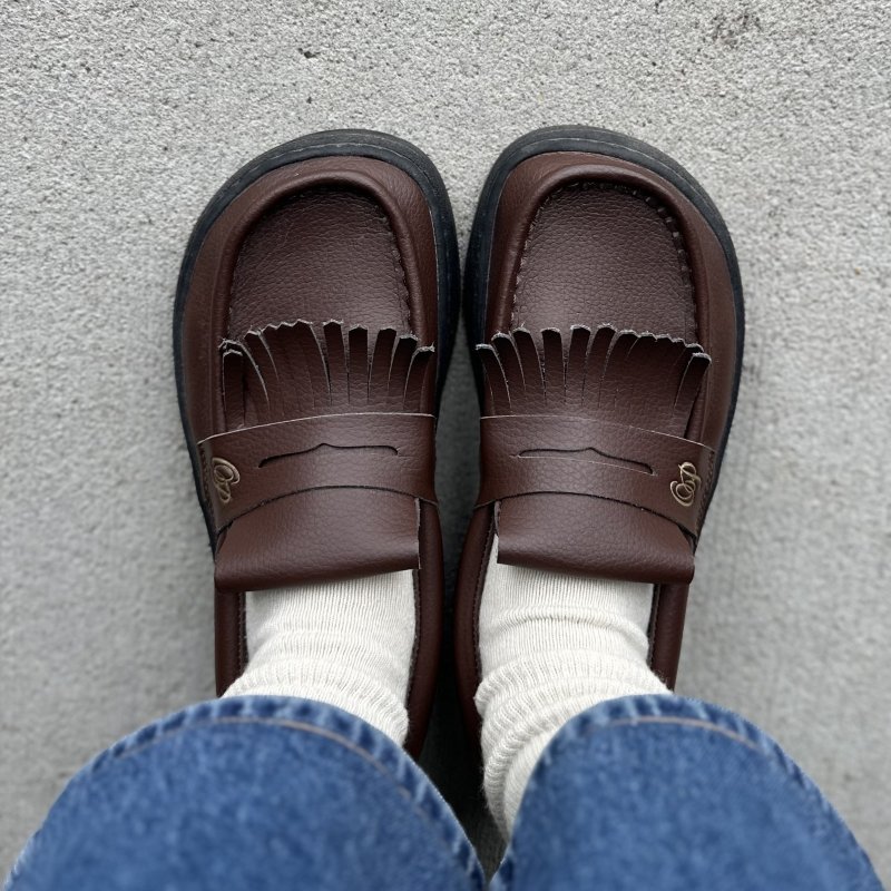 Top down view of a person in Ohne Project brown wide toe box loafers with fringe and being worn in scrunchy socks and wide leg cropped jeans