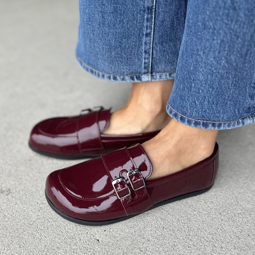 Side view of a person in patent red loafers from Peerko. the Flare model features a double buckle strap and a wide toe box.